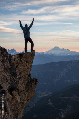 Adventurous man on top of the mountain during a vibrant sunset. Taken on Cheam Peak  near Chilliwack  East of Vancouver  British Columbia  Canada.