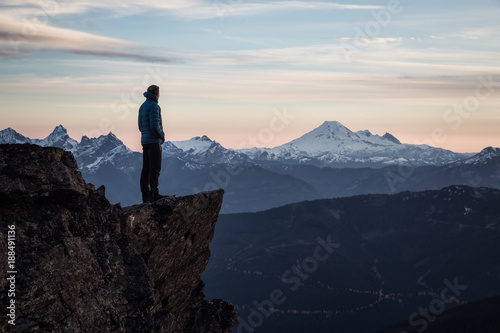 Adventurous man on top of the mountain during a vibrant sunset. Taken on Cheam Peak  near Chilliwack  East of Vancouver  British Columbia  Canada.