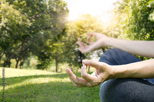 Hands of woman meditating in a yoga pose on park background