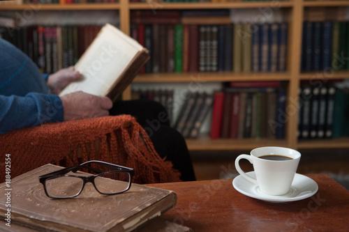 Sweet moments of relaxation with books and a cup of coffee. Vintage books, glasses, chair, library, man