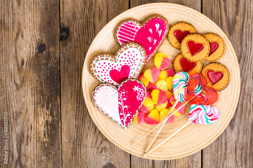 Set of sweets in the shape of heart on plate on wooden background
