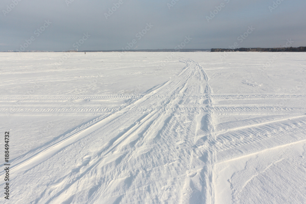 Trace of a snowmobile on a snowy surface of frozen reservoir at dawn, Ob reservoir, Siberia, Russia