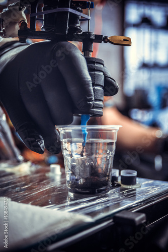 Hand of tattoo artist with a tattoo machine.