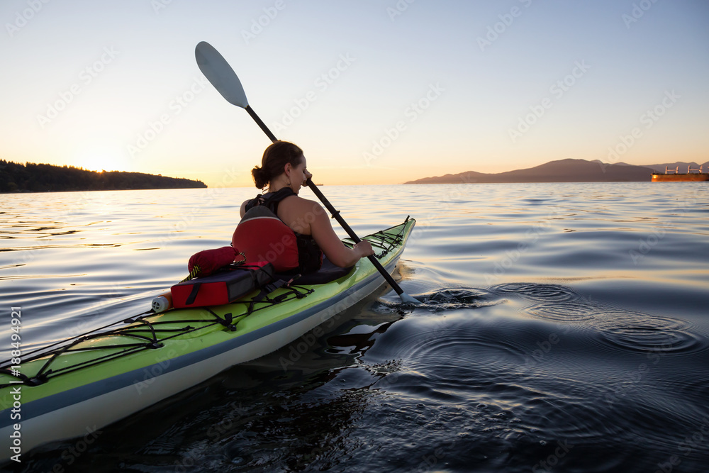 Girl Kayaking during a colorful and vibrant Sunset. Taken near Jericho Beach, Vancouver, British Columbia, Canada.