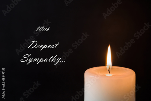 Condolence card with text. Candle with flame on the dark background. Sorrow concept.