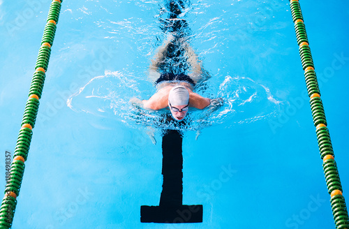 Senior man swimming in an indoor swimming pool.