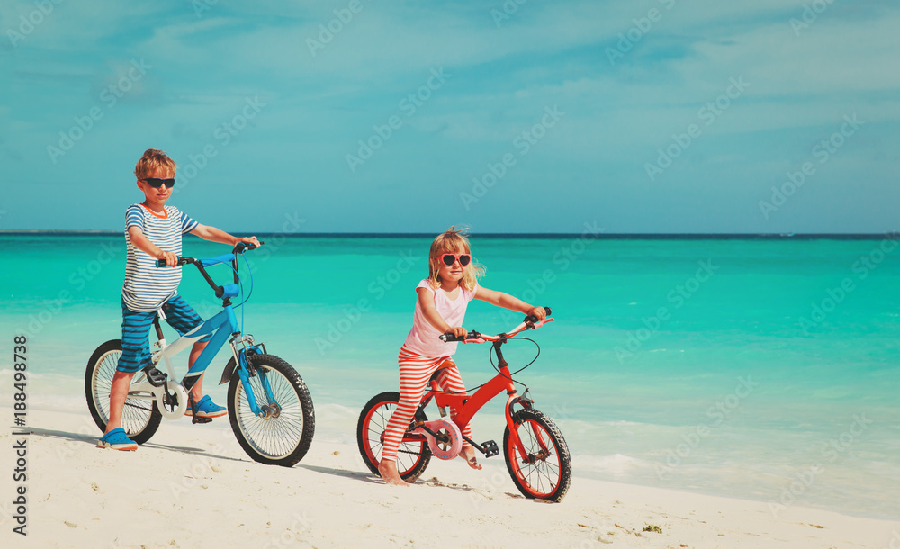 little boy and girl ride bike on beach