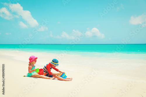 Fototapeta Naklejka Na Ścianę i Meble -  little boy and girl play with sand on beach