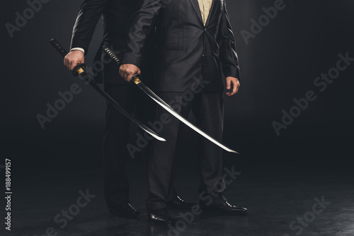 cropped shot of yakuza members with katana swords isolated on black photo