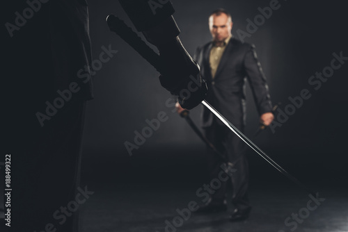 handsome modern samurai in suit ready to fight on black photo