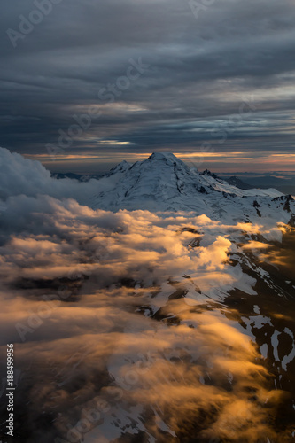 Dramatic Aerial view of a famous volcano that can be seen from Seattle and Vancouver, during a cloudy sunset. Located in Washington State, North America. 