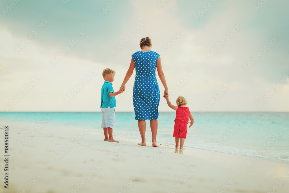 mother and two kids walking on beach