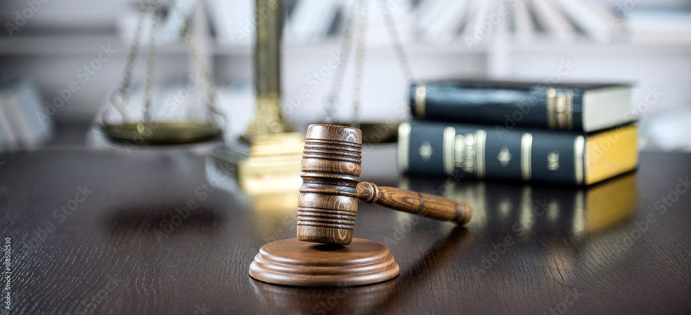 Law and Justice concept. Mallet of the judge, books, scales of justice. Gray stone background, reflections on the floor, place for typography. Courtroom theme.