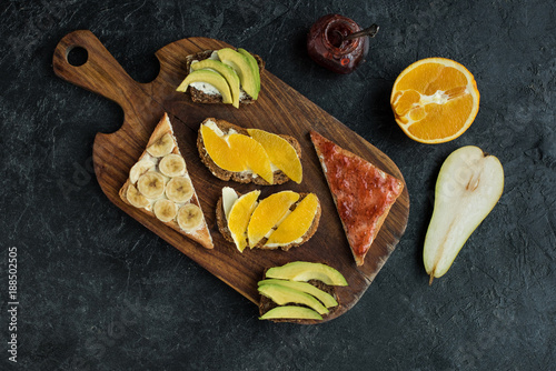 flat lay with snacks for healthy breakfast on wooden cutting board on dark tabletop