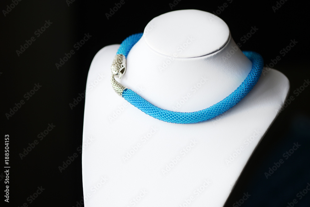 Blue beaded necklace with snake head lock on a dark background close up Blue beaded necklace with snake head lock on a dark background close up