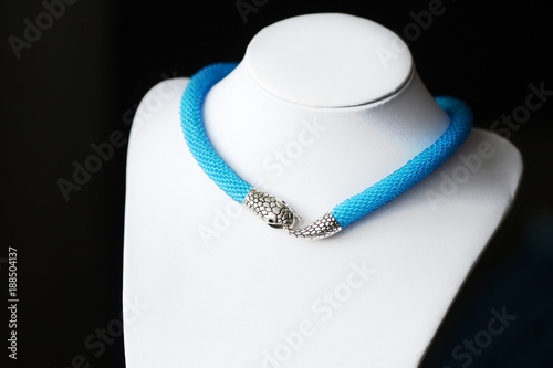 Blue beaded necklace with snake head lock on a dark background close up