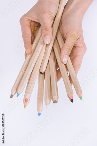 partial view of female hands holding colorful crayons isolated on white
