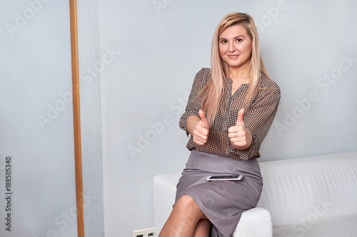 Attractive female showing thumbs up in an office