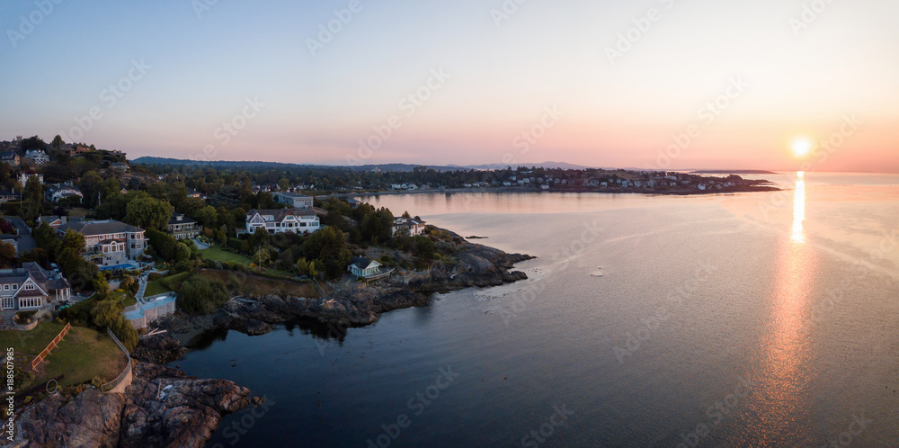 Aerial panoramic view of the luxury homes on a rocky Pacific Ocean Shore during a vibrant summer sunrise. Taken near Victoria, Vancouver Island, British Columbia, Canada.