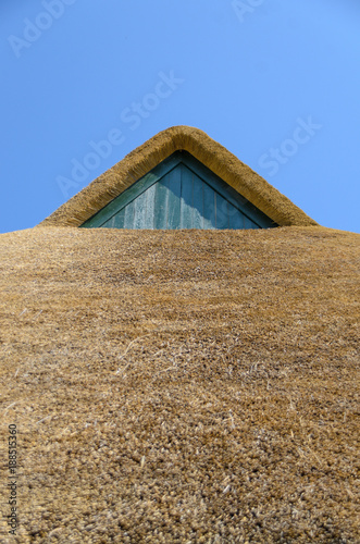 Photos Braunes Hausdach aus Reet (Schilfrohr) mit Holz-Gaube vor blauem und wolkenlosem