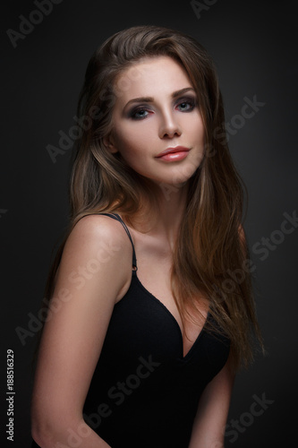 Beauty portrait of a chic woman with long straight hair isolated on a dark gray background.