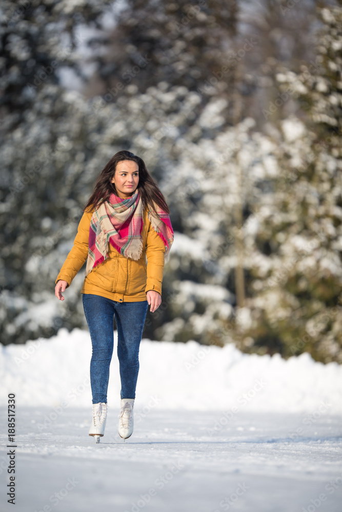 Young woman ice skating outdoors on a pond on a freezing winter day (color toned image; motion blurred image) Young woman ice skating outdoors on a pond on a freezing winter day (color toned image; motion blurred image)