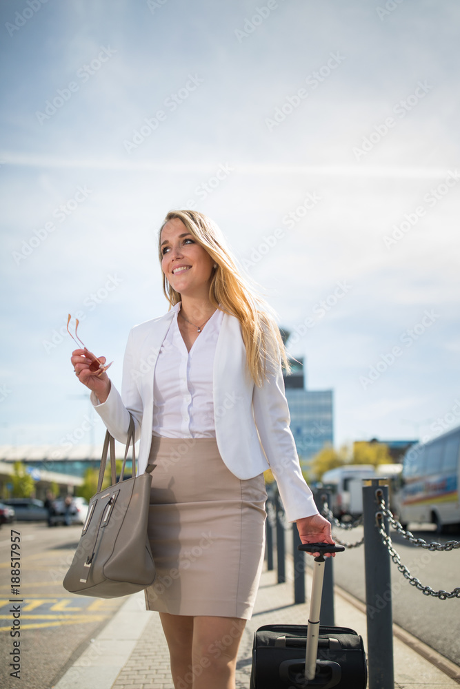 Fototapeta premium Young female passenger at the airport, walking to he departure terminal from a parking lot (color toned image)