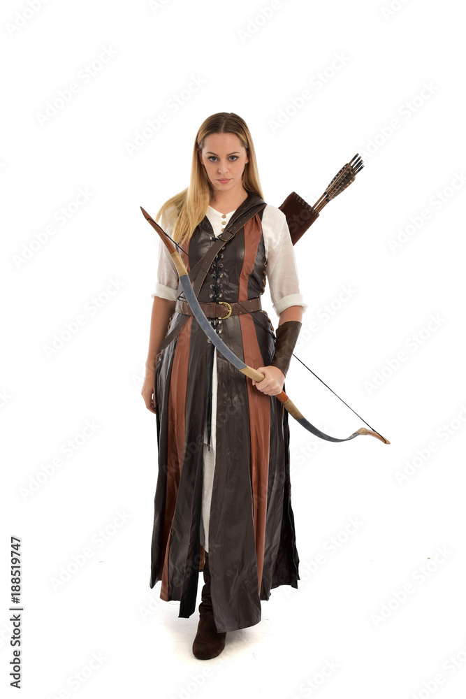 full length portrait of girl wearing brown  fantasy costume, holding a bow and arrow. standing pose on white studio background. 