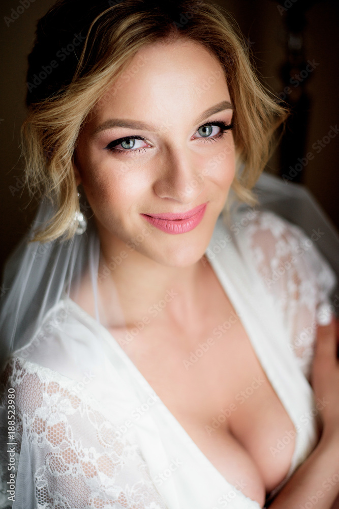 Seductive bride in a silk robe stands before a window Seductive bride in a silk robe stands before a window