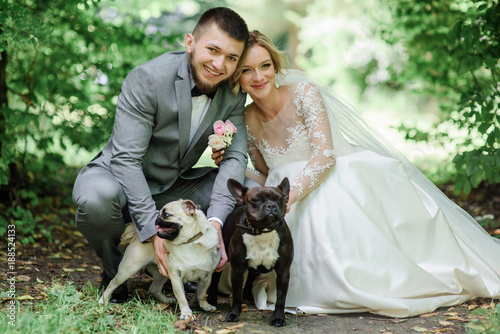 Photography Bride and groom play with fluffy dogs standing in the forest