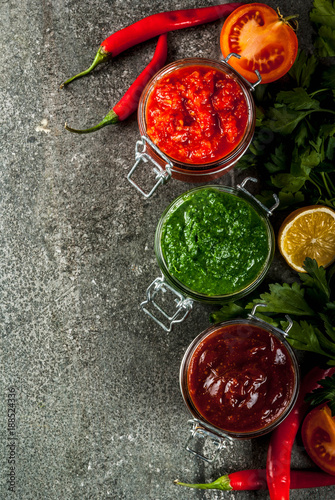 Indian traditional food, Set of three chutney for Chaat and Sev Puri - sweet date-tamarind, cilantro-mint green and red chilli garlic, On dark stone background, copy space top view