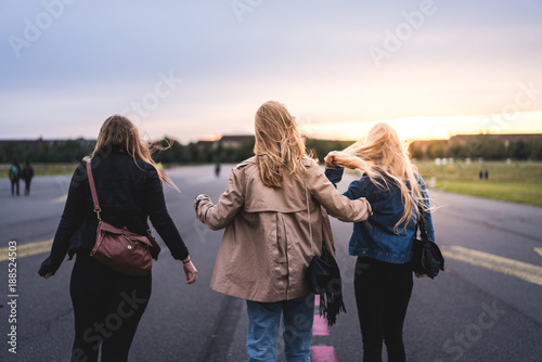 three blond young girls walking into the sunset in Berlin