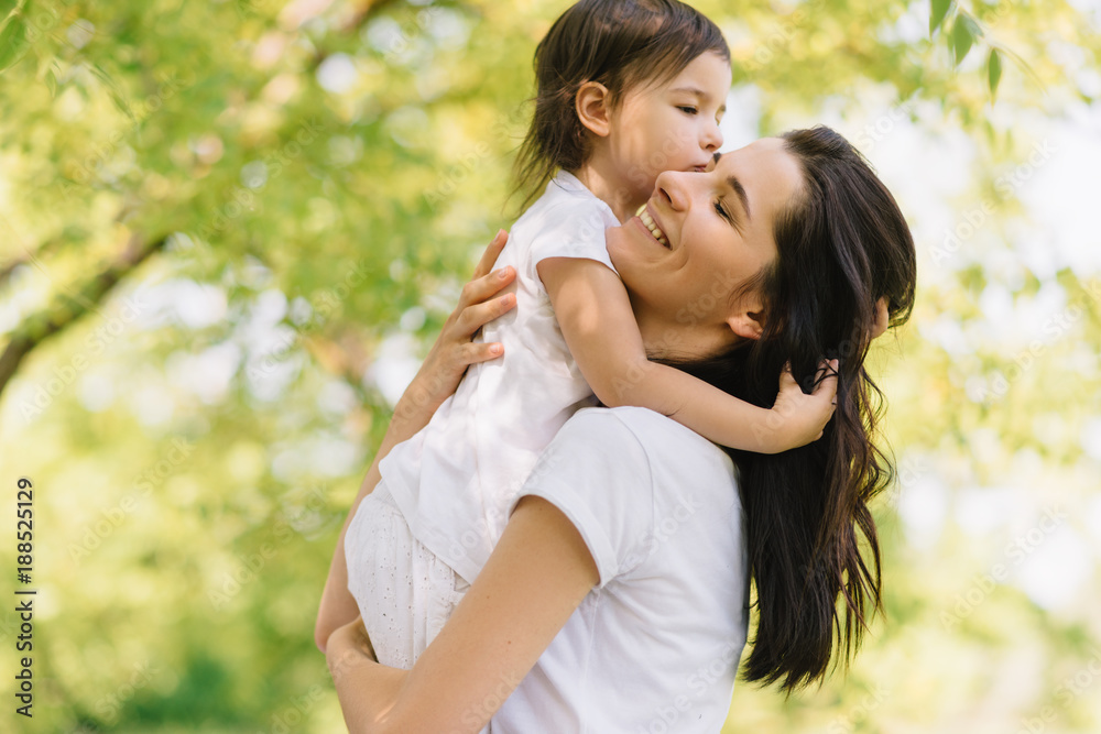 Candid shot of cheerful beautiful mother and her cute daughter playing outdoors, holding each other. Mom and her pretty kid playing in the park together. Portrait of good relationship in family. Candid shot of cheerful beautiful mother and her cute daughter playing outdoors, holding each other. Mom and her pretty kid playing in the park together. Portrait of good relationship in family.