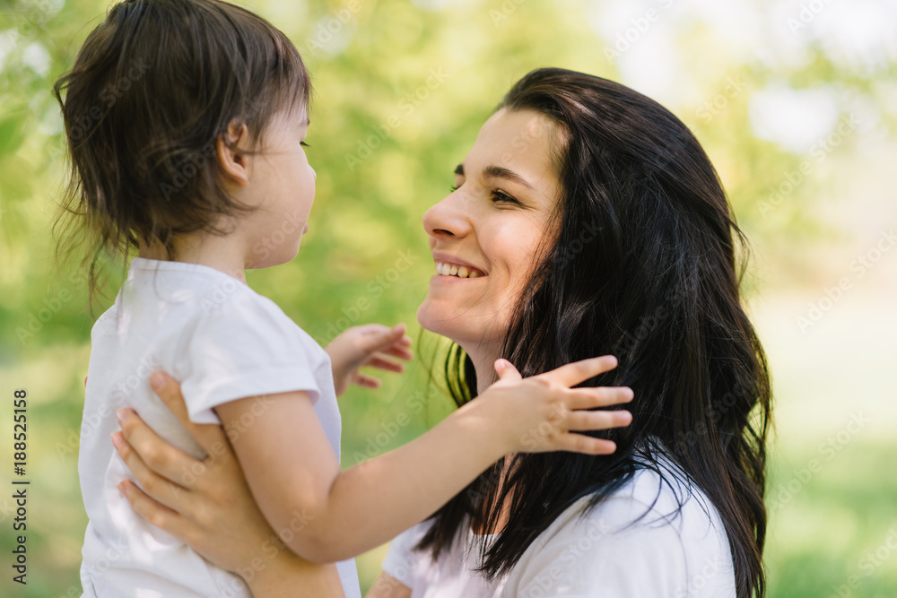 Close-up shot of cheerful beautiful mother and her cute daughter playing outdoors, holding each other. Mom and her pretty kid playing in the park together. Portrait of good relationship in family. Close-up shot of cheerful beautiful mother and her cute daughter playing outdoors, holding each other. Mom and her pretty kid playing in the park together. Portrait of good relationship in family.