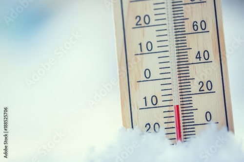 Thermometer on snow shows low temperatures under zero. Low temperatures in degrees Celsius and fahrenheit. Cold winter weather ten under zero.