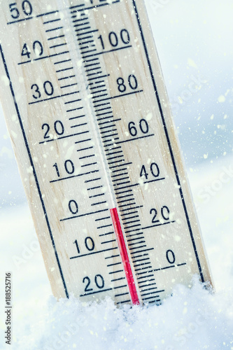 Thermometer on snow shows low temperatures zero. Low temperatures in degrees Celsius and fahrenheit. Cold winter weather twenty zero