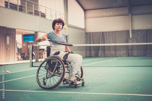 Disabled mature woman in wheelchair on a tennis court © Nejron Photo