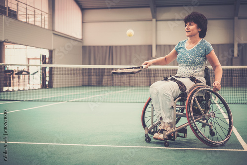 Disabled mature woman in wheelchair on a tennis court