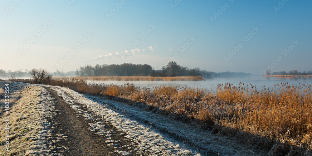A cold morning at sunrise. A frosted path along the river.