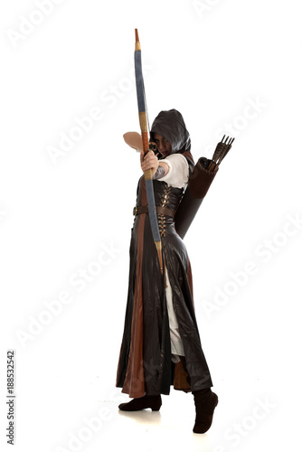 full length portrait of girl wearing brown fantasy costume, holding a bow and arrow, on white studio background. 