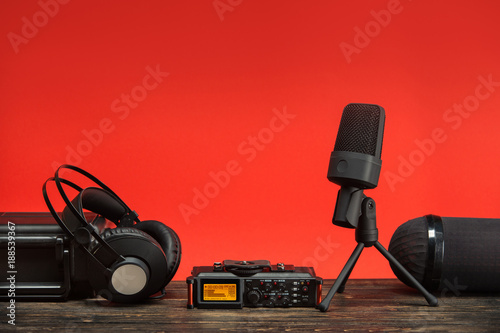 equipment for field audio recording on red background.  usb microphone, recorder, headphones, portable case and windshield