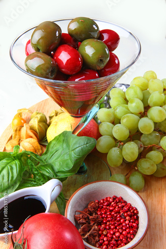 Obraz na płótnie Grapes, large olives, tomato and apple on a wooden board