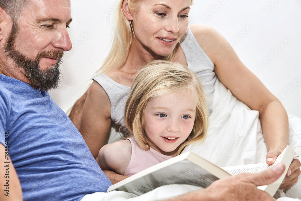 Happy family in bed reading book together Happy family in bed reading book together