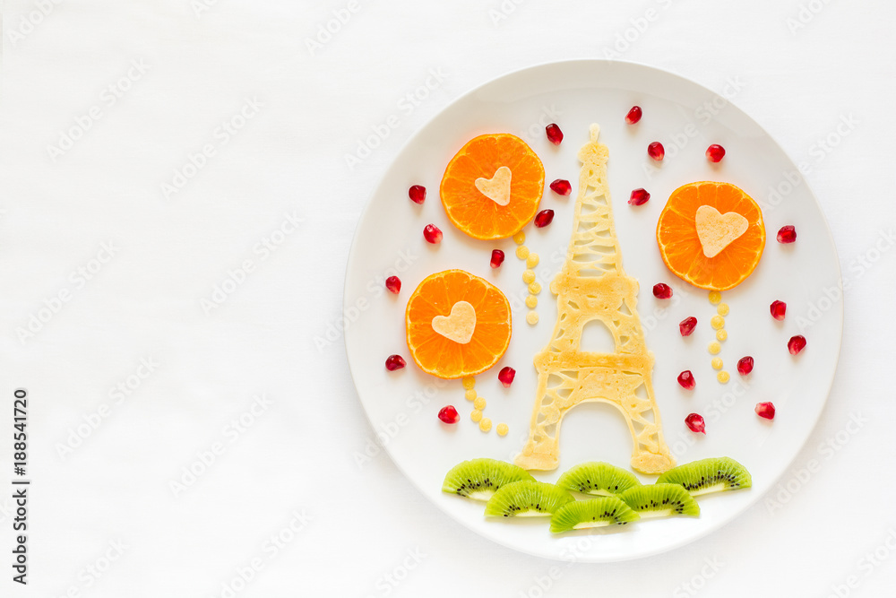 Art food concept. Eiffel Tower with silhouette of a couple in love and heart shaped balls. Lace pancakes with pomegranate seeds. Top view. Flat lay. Space for copy