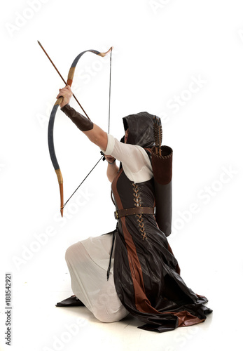 full length portrait of girl wearing brown  fantasy costume, holding a bow and arrow, on white studio background.  © faestock