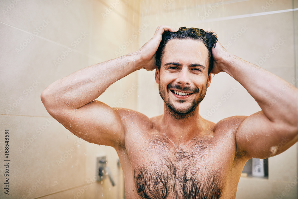 Portrait of athletic young man smiling and looking at camera while standing in the shower Portrait of athletic young man smiling and looking at camera while standing in the shower