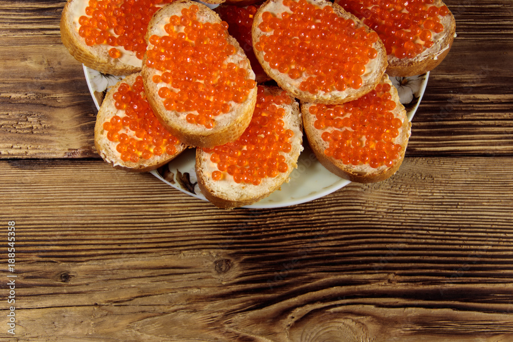 Sandwiches with butter and red caviar on wooden table Sandwiches with butter and red caviar on wooden table