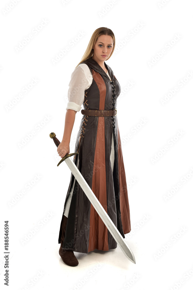 full length portrait of girl wearing brown fantasy costume, holding a sword. standing pose on white studio background. full length portrait of girl wearing brown fantasy costume, holding a sword. standing pose on white studio background.