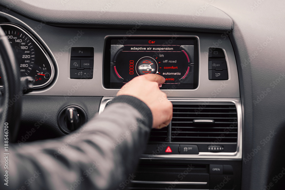 Modern luxury prestige car dashboard. Close up man's hand chooses the style of driving on the board computer of the car. Modern luxury prestige car dashboard. Close up man's hand chooses the style of driving on the board computer of the car.