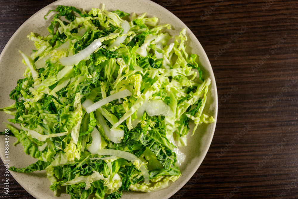 Salad with savoy cabbage and onion on wooden table